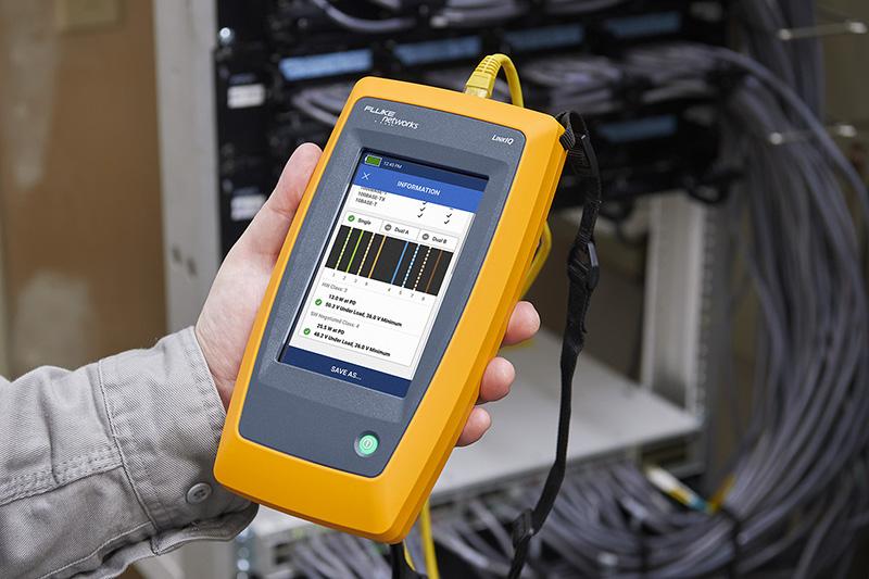 Technician holding a Fluke LinkIQ network cable tester displaying test results in front of a server rack.